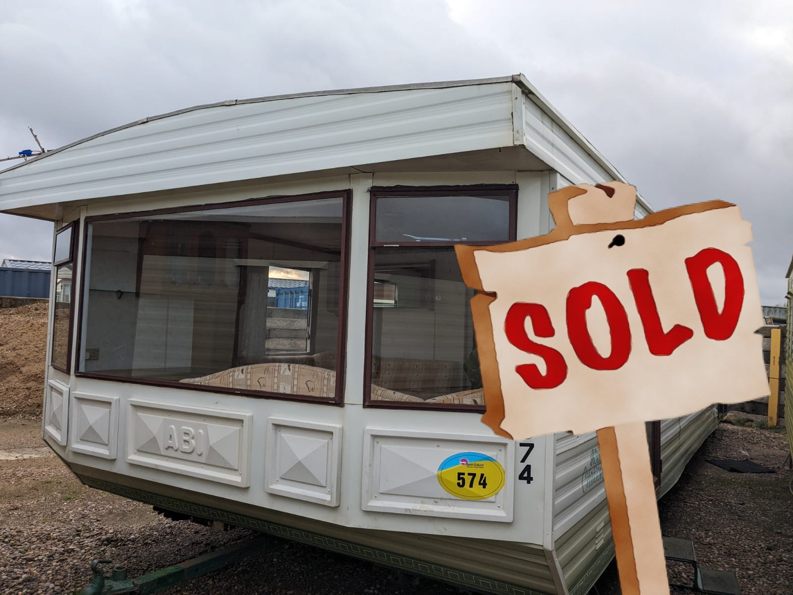 An ABI Citation static caravan on gravel, with the original website's SOLD sign