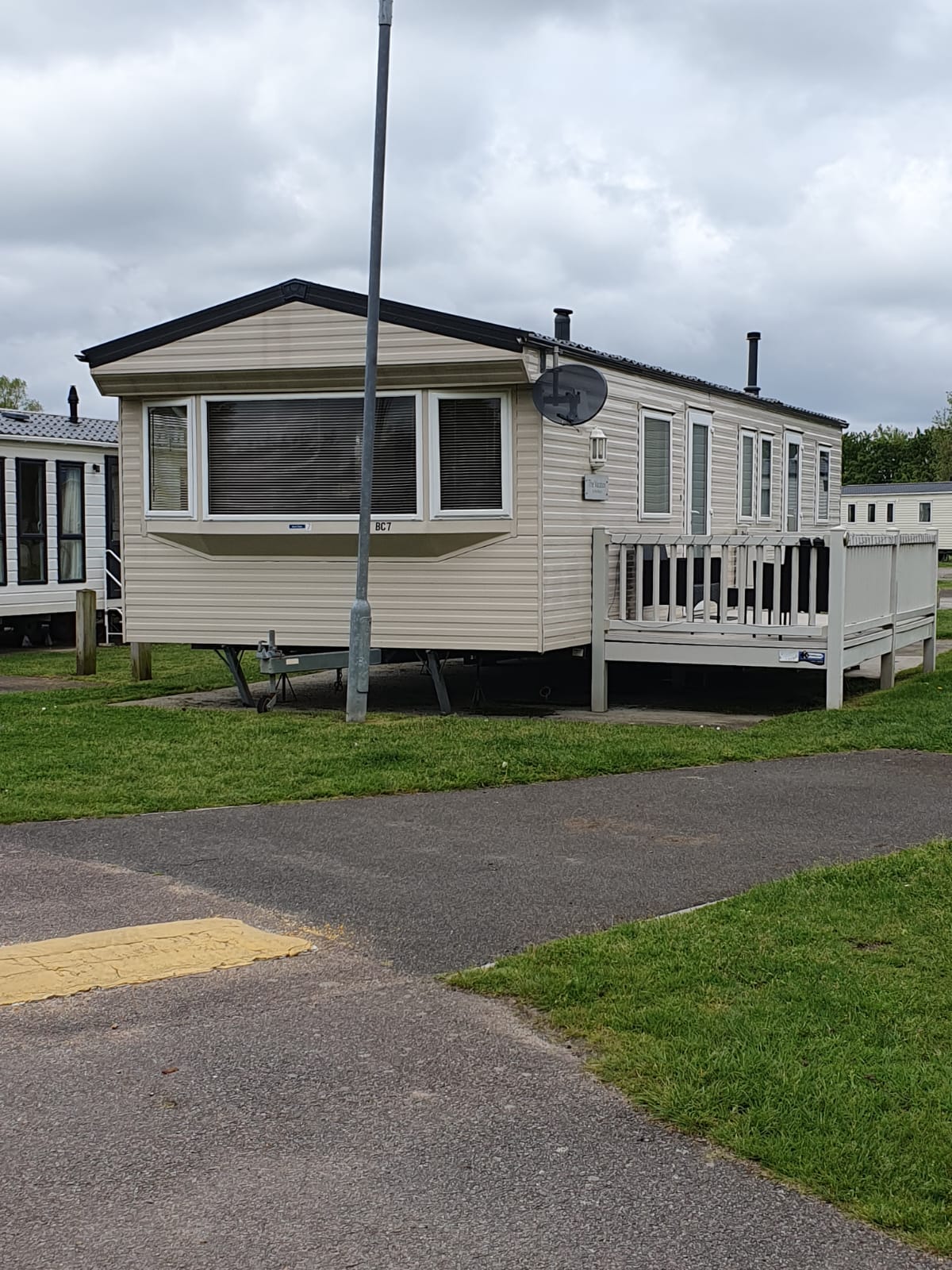 The Vacation, a used static caravan with a raised deck, on its pitch at a holiday park