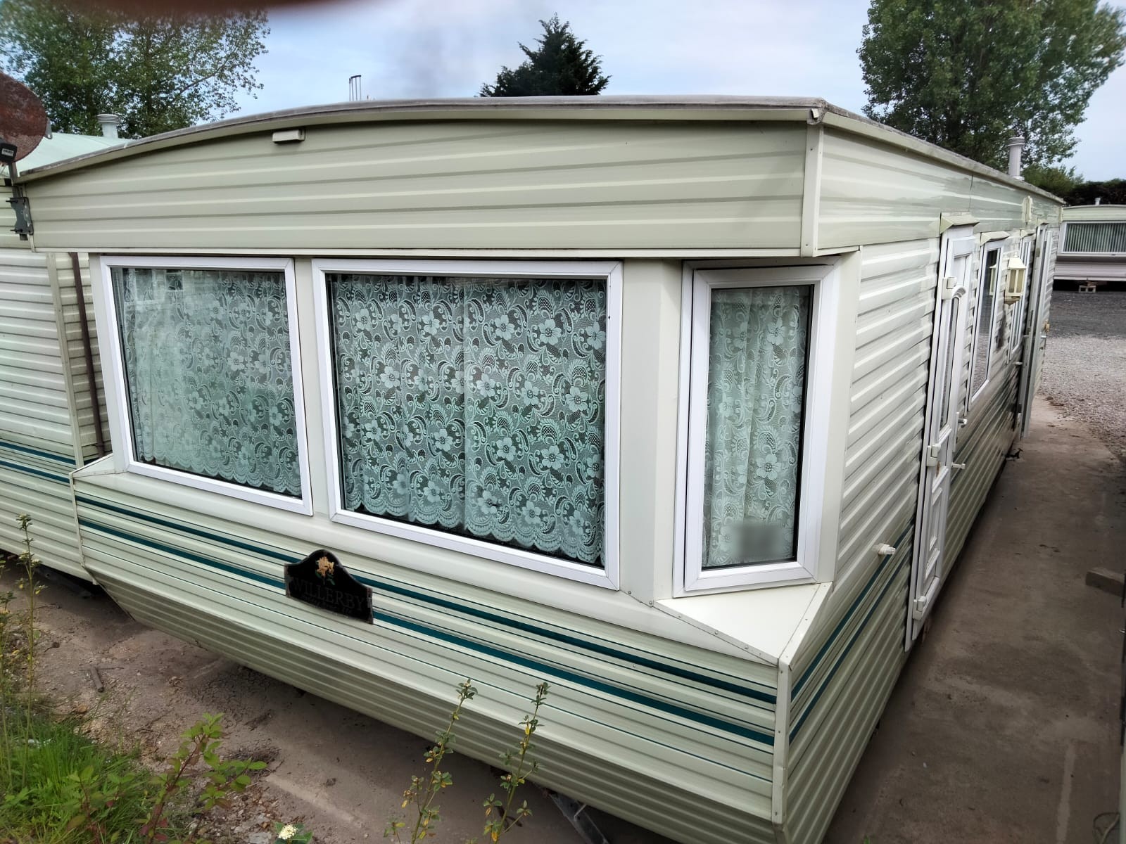 The Willerby Westmorland on gravel, with lace curtains at its windows